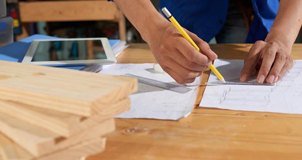 cropped man wearing blue overall drawing furniture sheet pape 1