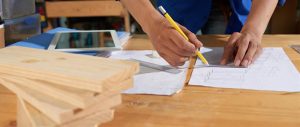 cropped man wearing blue overall drawing furniture sheet pape 1